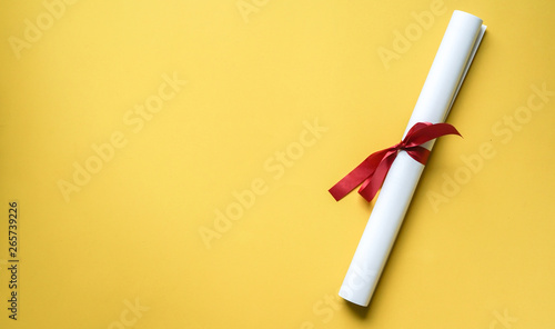 close up top view of certificated degree on yellow background for education concept photo