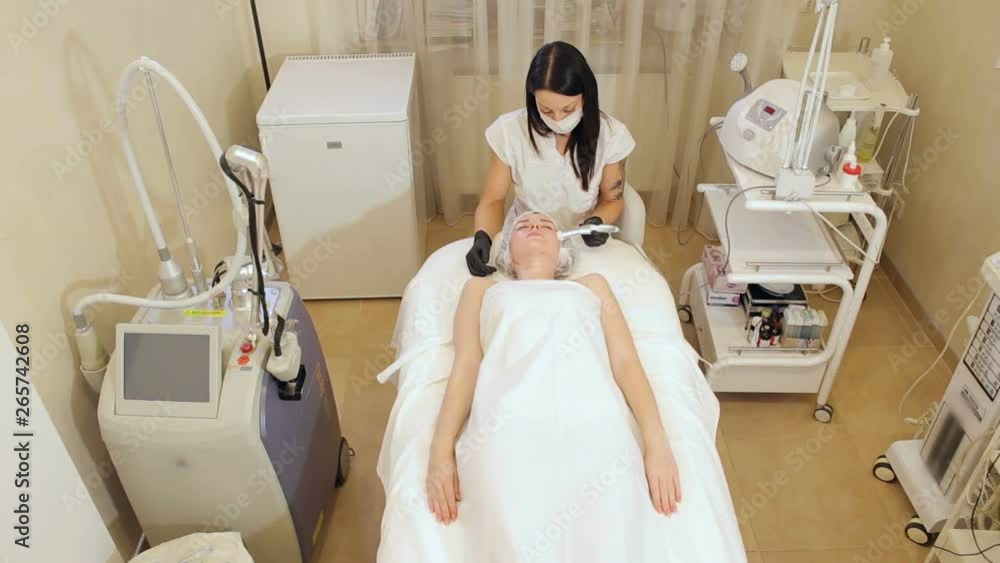A woman cosmetologist works with a client in a Spa salon, she splashes a moisturizing liquid on her skin and makes non-injection mesotherapy. Needle mesotherapy. A woman cosmetologist works with a client in a Spa salon, she splashes a moisturizing liquid on her skin and makes non-injection mesotherapy. Needle mesotherapy.