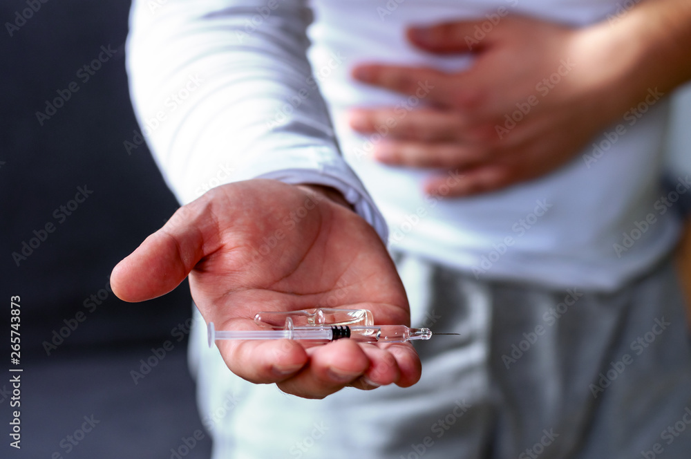 A man holds his stomach, stretches his hand with pills. Health, illness, medicine.