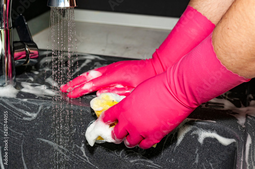 The process of washing the dark sink, hands close-up. A man in pink gloves washes a sink. Cleaning, clean up.