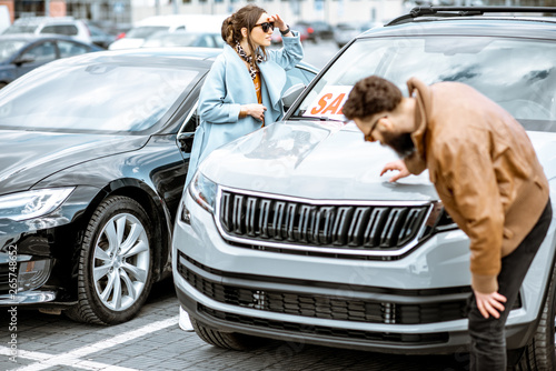 фотографія Young stylish couple choosing luxury car to buy on the open ground of the dealer