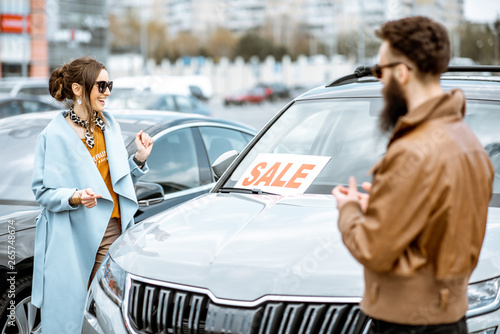 Obraz na plátně Young stylish couple choosing luxury car to buy on the open ground of the dealer