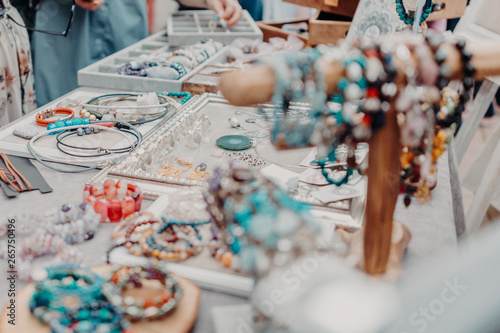 Multicolored jewelry, bracelets lying on the table and hanging on a stand. Flat lay. Horizontal orientation. Shallow focus.
