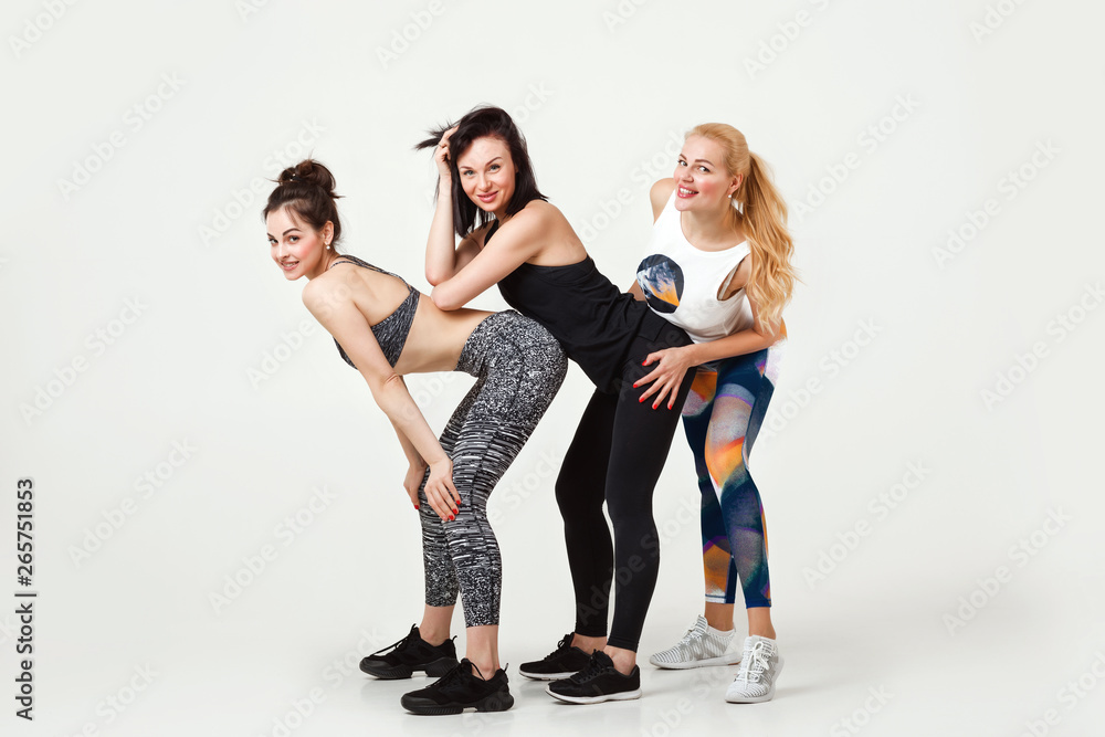 Fototapeta premium Group of sporty female friends resting after fitness on white background