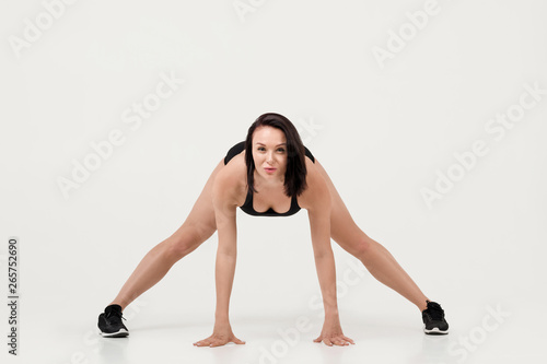 Muscular fit young woman doing stretching exercises isolated on white background