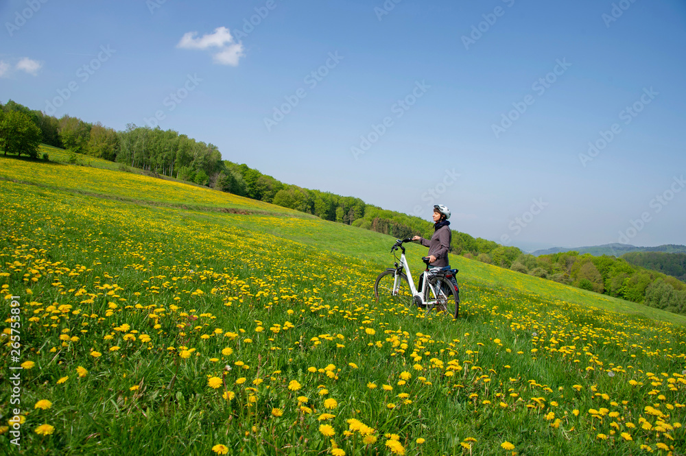 Fahrrad Fahrerin macht Pause , mitten in blühender Frühlingswiese Fahrrad Fahrerin macht Pause , mitten in blühender Frühlingswiese