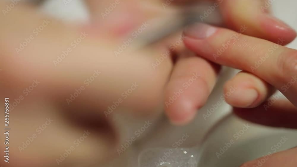 Manicure. Close-up of manicurist hands removing cuticle from female nails with professional metal nail scissors. Manicure. Close-up of manicurist hands removing cuticle from female nails with professional metal nail scissors.