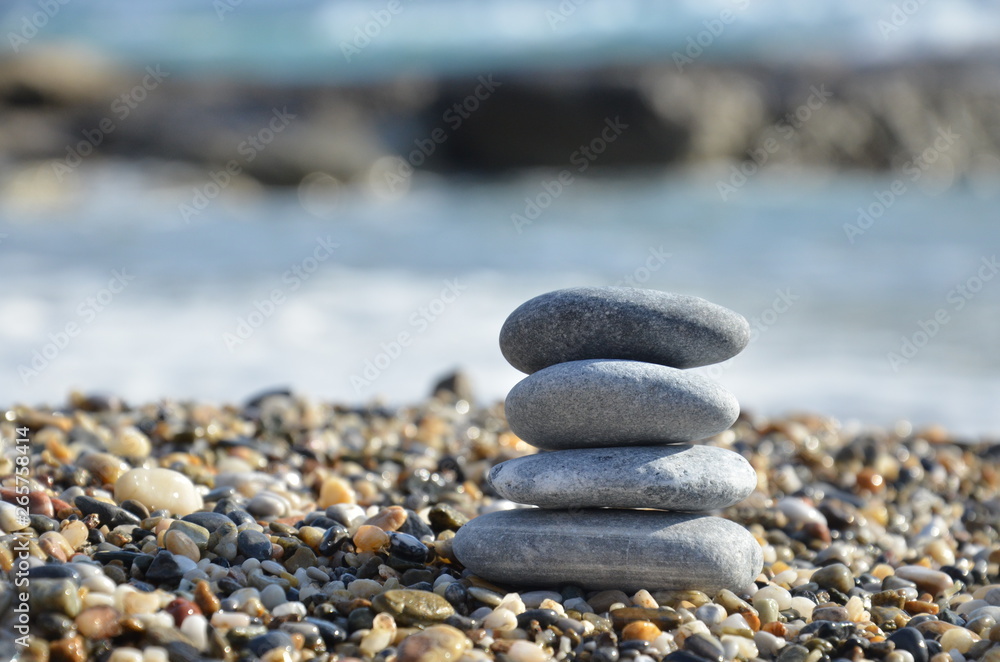 Zen pyramid of spa stones on the blurred sea background. Sand on a beach. Sea shores. Water waves texture. Place for text. concept of balance and spirituality Zen pyramid of spa stones on the blurred sea background. Sand on a beach. Sea shores. Water waves texture. Place for text. concept of balance and spirituality