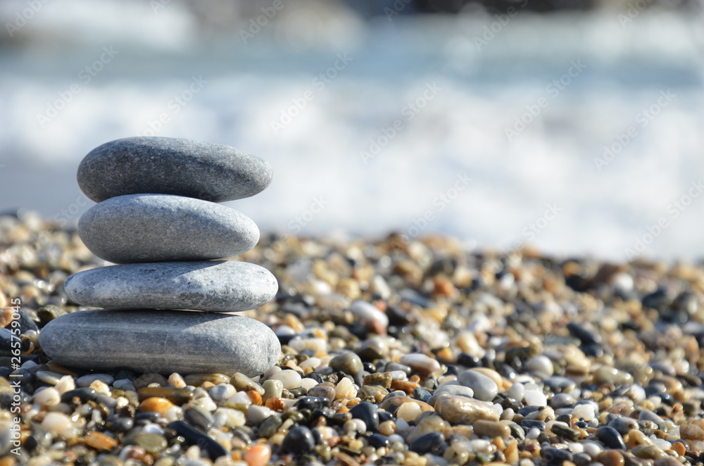 Zen pyramid of spa stones on the blurred sea background. Sand on a beach. Sea shores. Water waves texture. Place for text. concept of balance and spirituality Zen pyramid of spa stones on the blurred sea background. Sand on a beach. Sea shores. Water waves texture. Place for text. concept of balance and spirituality