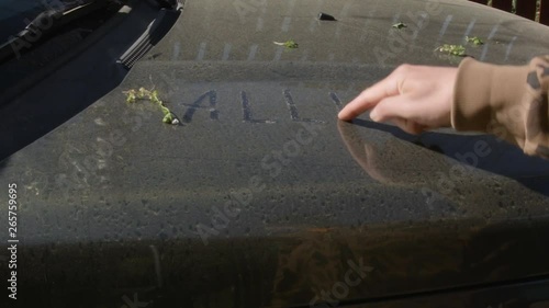 A hand writing word Allergy on a car hood covered with pollen
