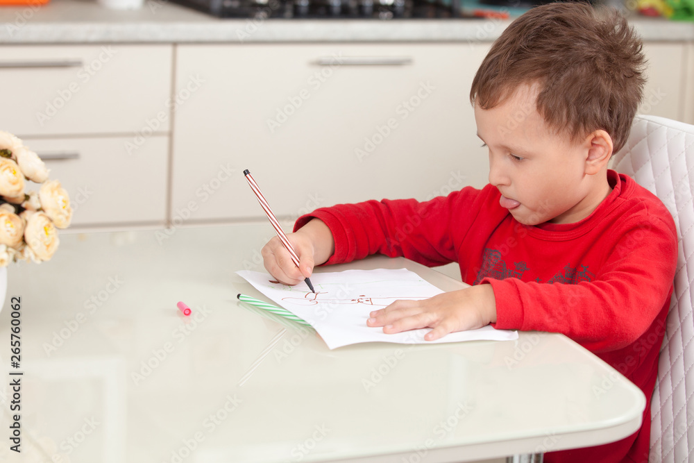 Inspired by the boy draws a picture on the paper at the table Inspired by the boy draws a picture on the paper at the table