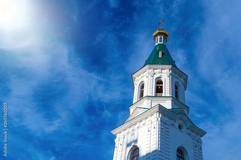 The bell tower of the Orthodox church in the Russian city of Omsk, illuminated by the rays of the sun