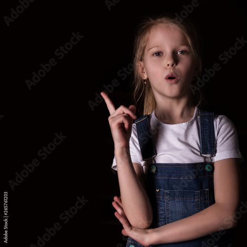 beautiful blonde little girl on a dark background. She stands in different poses and shows different emotions. free space for your text