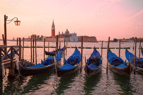 Moored gondolas on the background of the Cathedral of San Giorgio Maggiore on sunrise. Venice, Italy