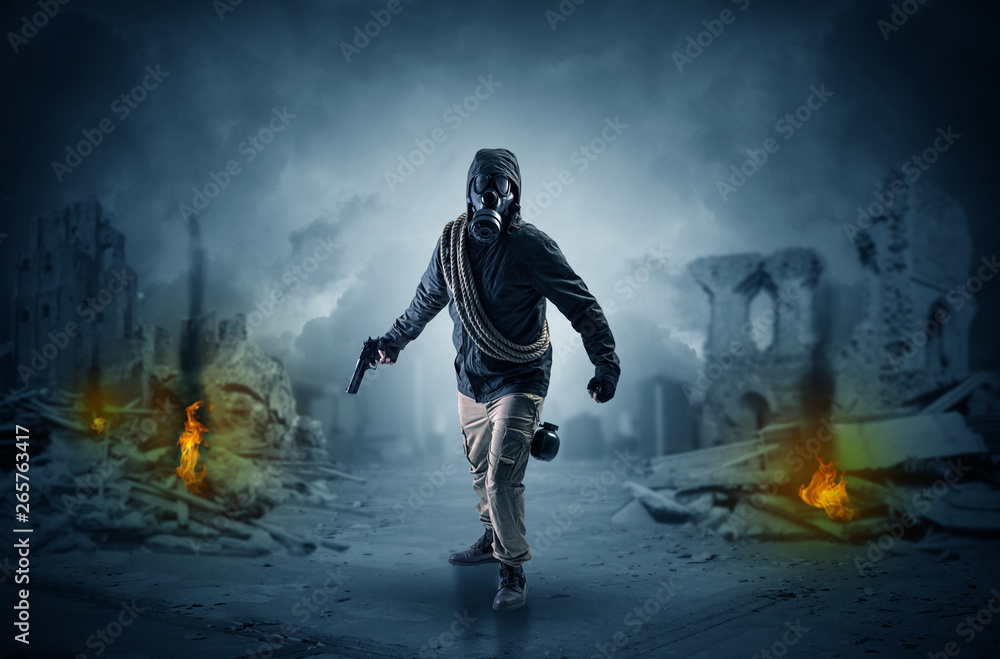 Fototapeta premium Destroyed place after a catastrophe with man in gas mask and weapon on his hand 