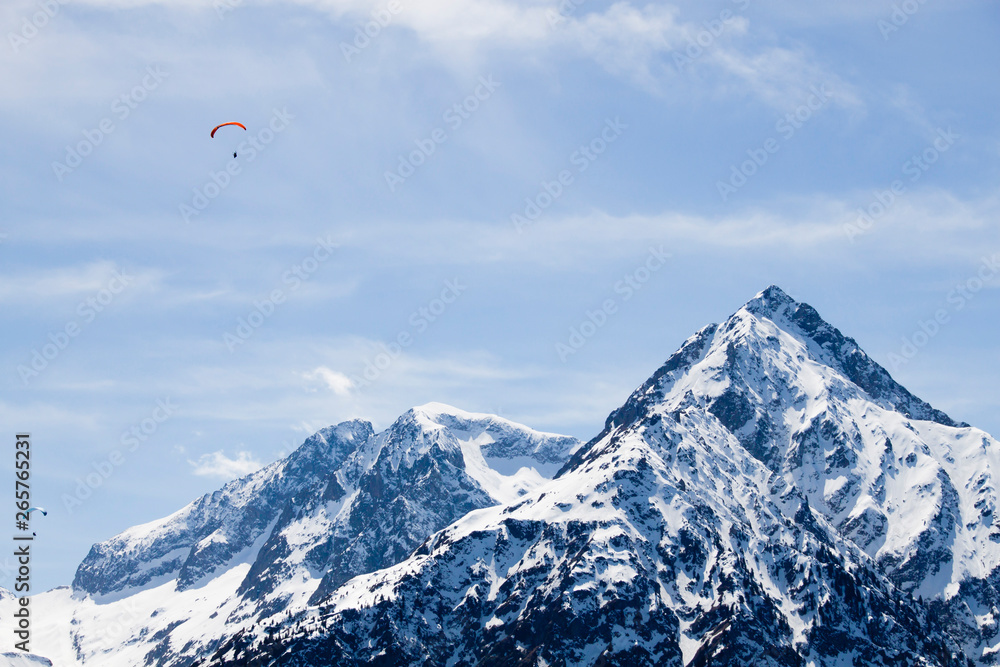 two parachutes flying in the sky over a snowed mountain two parachutes flying in the sky over a snowed mountain