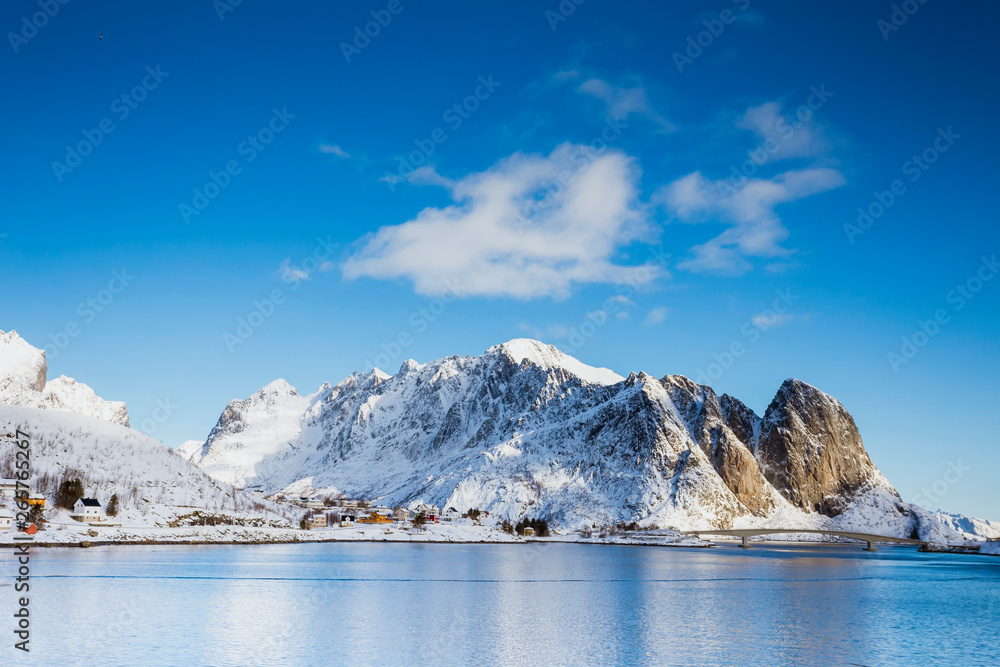A small settlement by the sea in a quiet bay with high mountains in the Lofoten Islands.