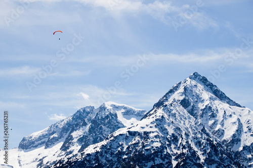 two parachutes flying in the sky over a snowed mountain