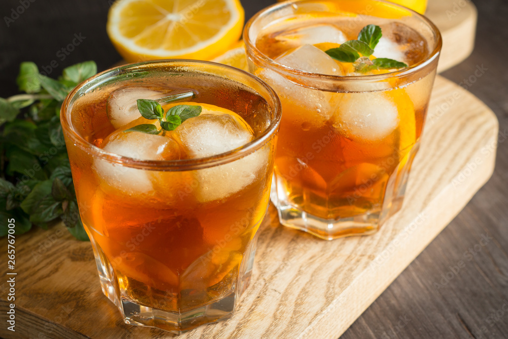 Glasses of cold ice tea with lemon, ice, mint on background. Homemade lemonade. Spring and summer drinks and beverages concept. Glasses of cold ice tea with lemon, ice, mint on background. Homemade lemonade. Spring and summer drinks and beverages concept.