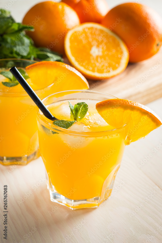 Fototapeta premium Photo of fresh orange juice in the glass jar. Summer healthy organic drink concept. Cold beverages with ice and orange fruits.