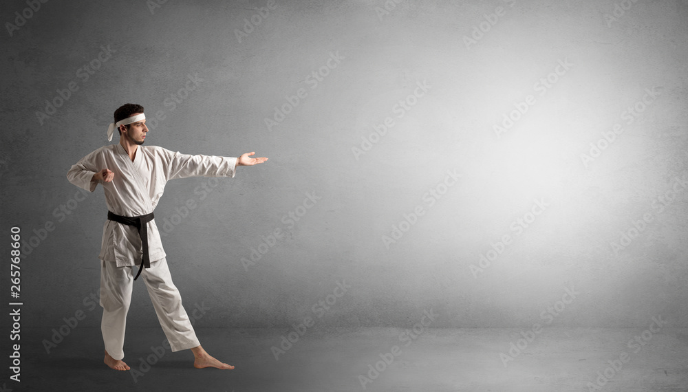 Small karate man fighting in an empty grey copy space