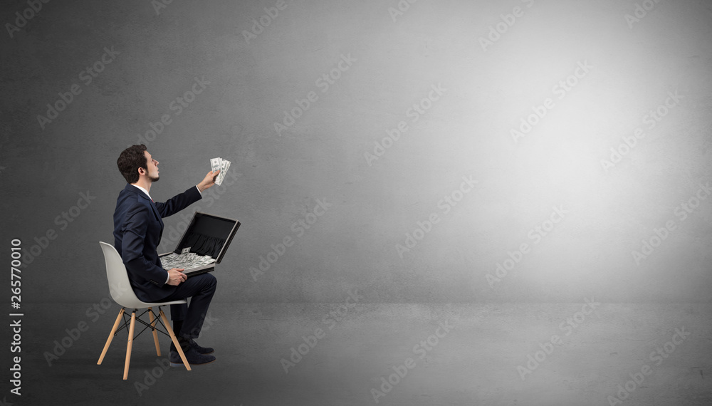 Businessman staying in an empty grey dark room with stuffs on his lap
