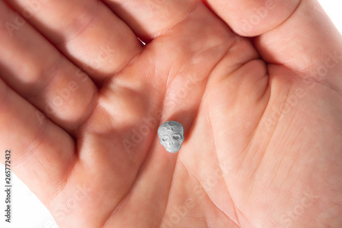 Top view of a caucasian hand with one grey MDMA, Amphetamine, Army Skull, Ecstasy, XTC pill.