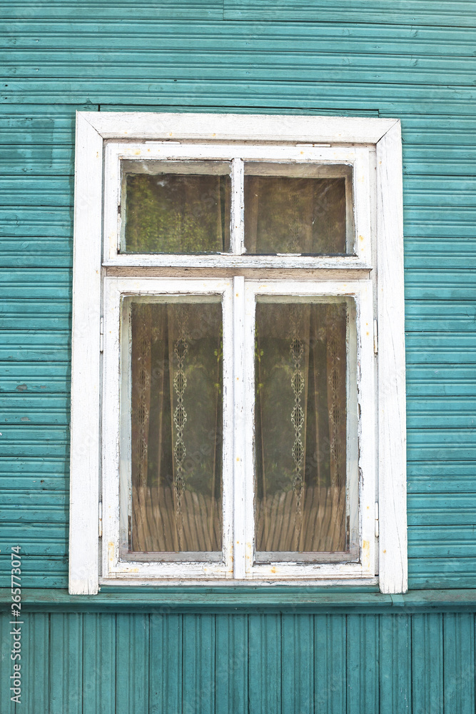 Rustic window in wooden village cottage house. Grunge weathered, abandoned blue paint wood wall background.