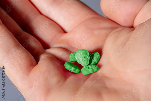 Close-up of the palm of a caucasian hand with green MDMA, Amphetamine, Army Skull, Ecstasy or XTC pills. photo