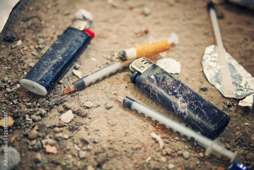 Used syringe on the ground - drugs Addiction equipment. Heroin, syringe, cigarette and lighter - drug addiction concept photo