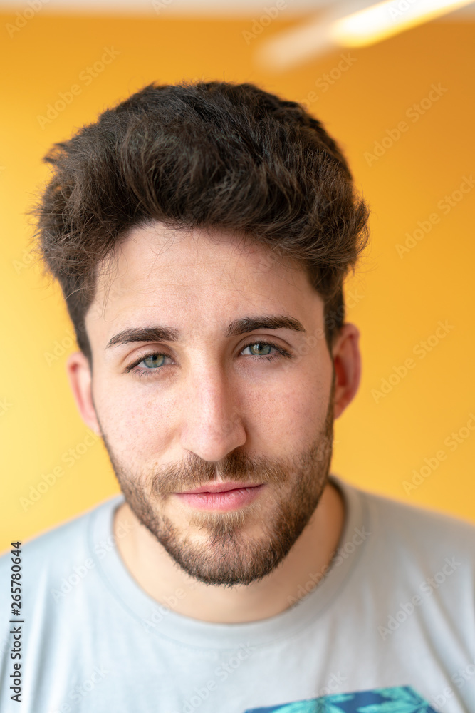 Close-up portrait of an attractive young man with green eyes staring with a yellow background Close-up portrait of an attractive young man with green eyes staring with a yellow background