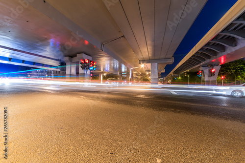 The light path of a car under a highway and a viaduct.