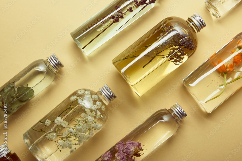 top view of transparent bottles with organic beauty products and dried wildflowers and herbs on yellow background top view of transparent bottles with organic beauty products and dried wildflowers and herbs on yellow background