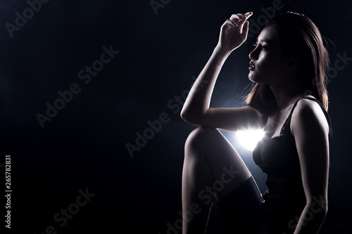 Healthy and Fit Sport Asian Woman in Bodysuit Underwear posing strong and bad feeling weight loss control  black corset body slim dress on asia girl. Studio lighting dark smoke background low exposure