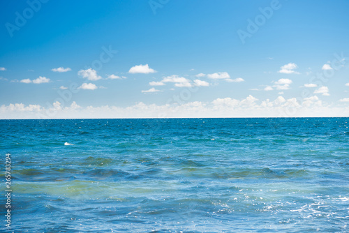 Seascape with blue water, sky and white clouds