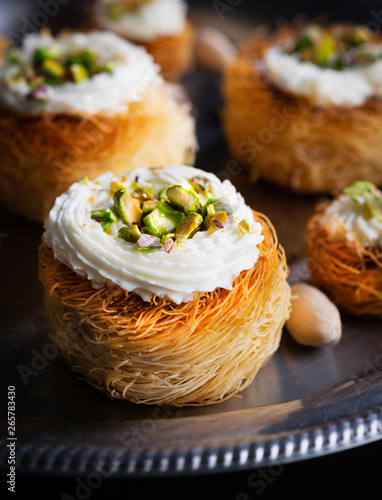 Kataifi, kadayif, kunafa, baklava pastry nest cookies with pistachios with tea. Cooking sweets turkish, or arabic traditional ramadan pastry dessert on a dark background.