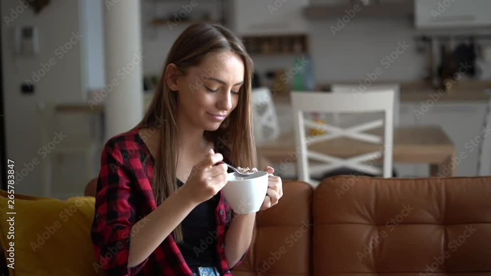 Beautiful young woman eats bowl of healthy granola Beautiful young woman eats bowl of healthy granola