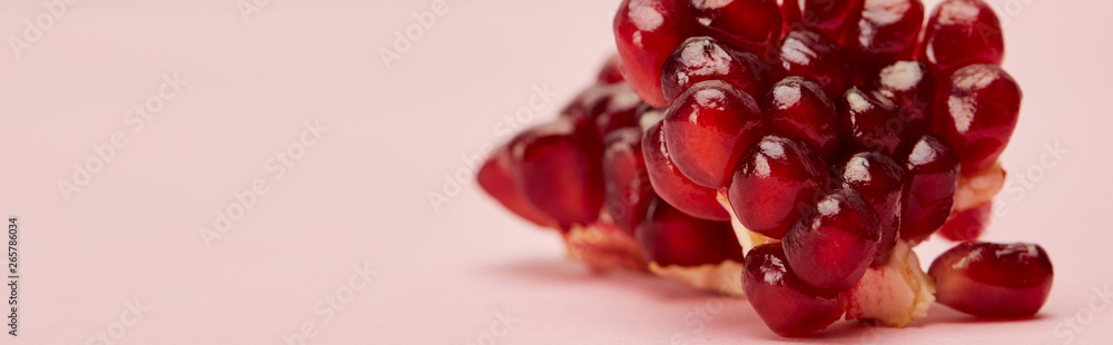 panoramic shot of ripe garnet on pink surface