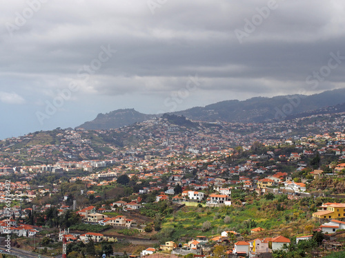 aerial cityscape view of the outskirts of funchal in Madeira with farms and houses with mountains and cloudy sky in the distance © Philip J Openshaw 