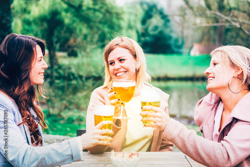 three females best friends sitting outdoor with a beer - carefree time and togetherness concept