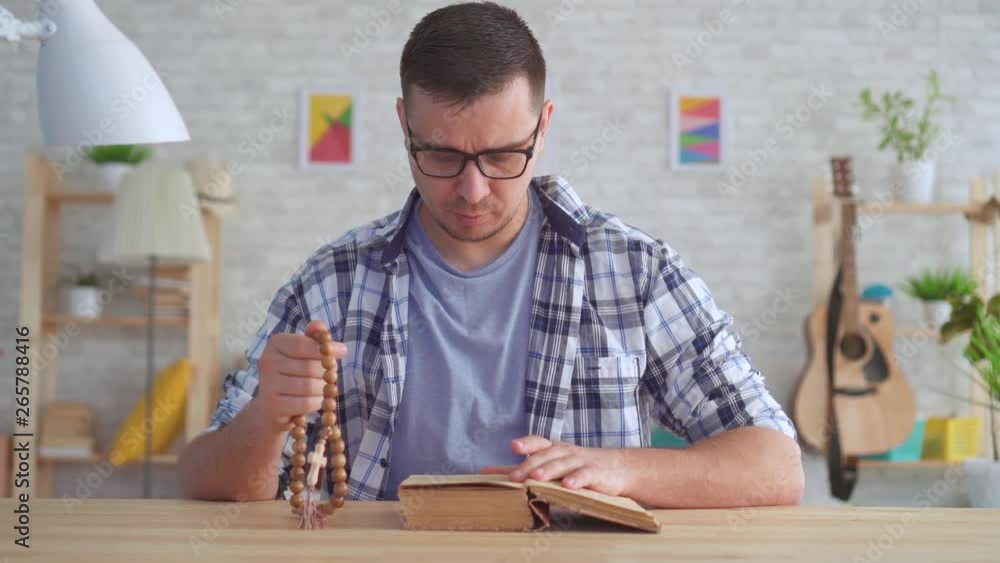 Portrait young man with glasses with a rosary in his hands and reading the Bible Portrait young man with glasses with a rosary in his hands and reading the Bible