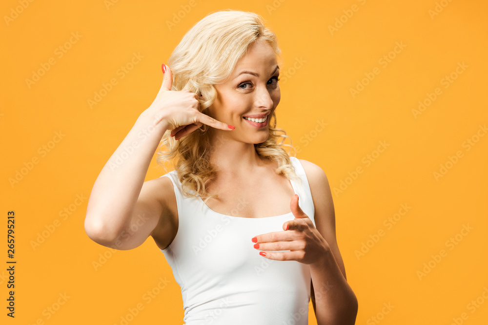 happy blonde woman pointing with finger and gesturing isolated on orange happy blonde woman pointing with finger and gesturing isolated on orange
