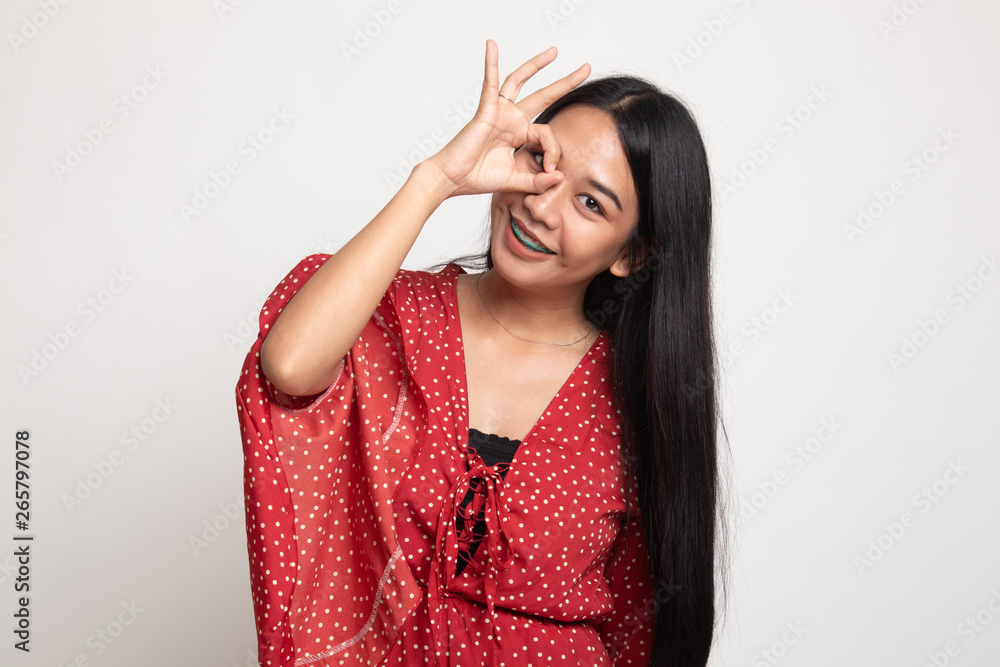 Beautiful young Asian woman show OK sign over her eye.