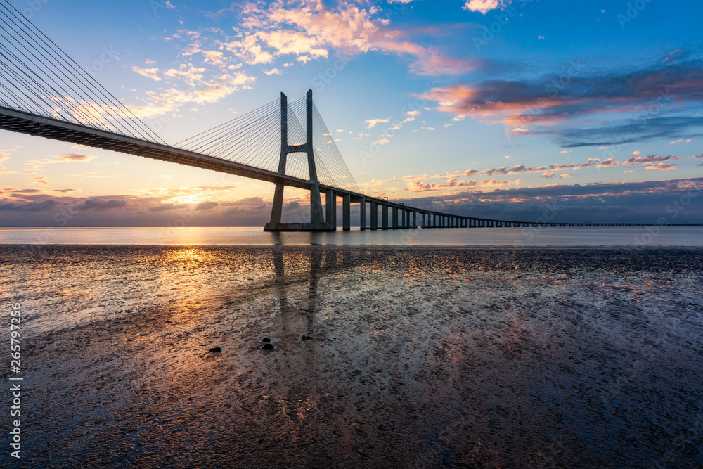 Obraz premium Vasco da Gama bridge at sunrise in Lisbon, Portugal. Vasco da Gama bridge in Lisbon by sunrise, Portugal. Sunrise at Lisbon, looking to the Vasco da Gama Bridge. Lisbon, Portugal.