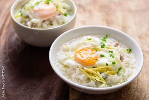 Thai rice soup or soft-boiled rice with pork and egg in the bowl on wooden background