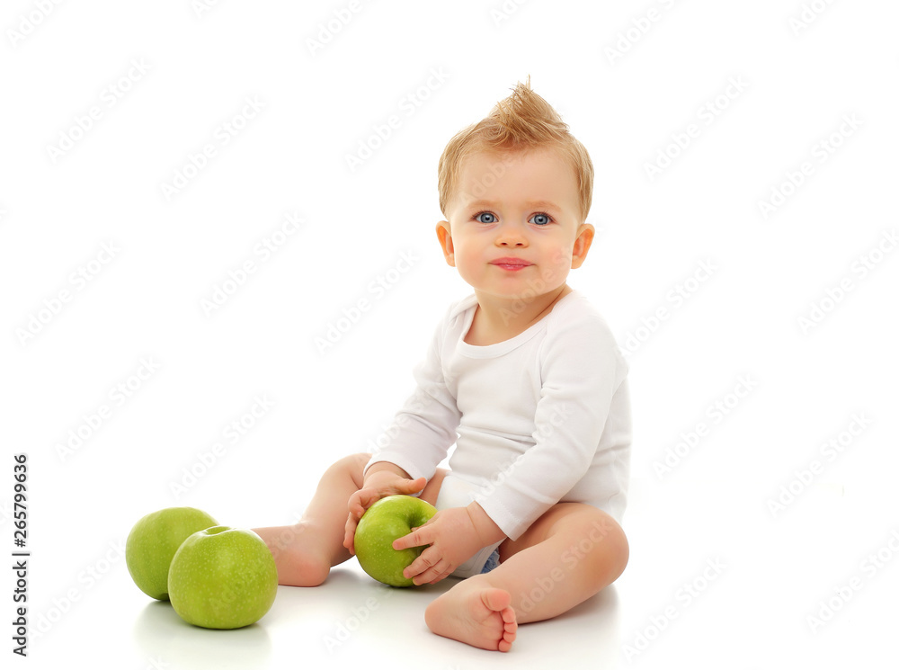 Baby 11 months old in white bodysuit sitting on white background with green apples Baby 11 months old in white bodysuit sitting on white background with green apples