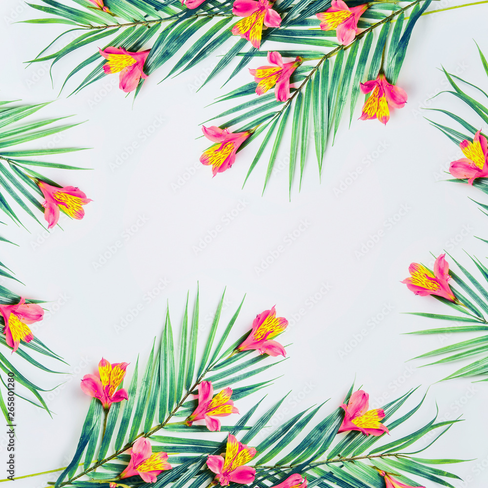 Fototapeta premium Tropical background with palm leaves and exotic flowers on white background, top view. Frame. Flat lay. Copy space for your design