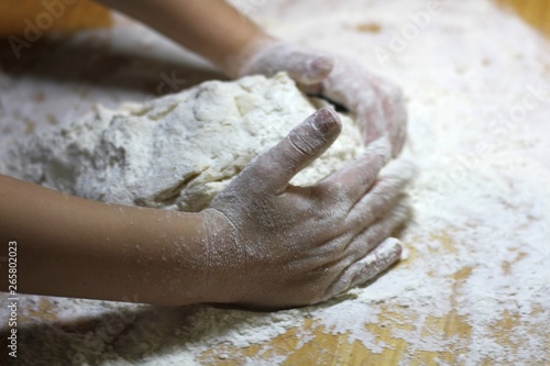 Children's hands and dough. Little boy kneading a dough. Healthy handmade food concept. bakery products, pizza, flour. cooking workshop. baby's hands roll out a dough on a wooden table.