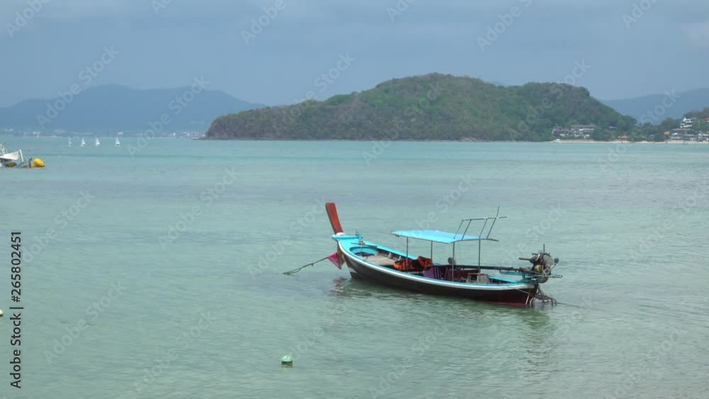 View off the Coast of Phuket Thailand, Thai long tail boats in water on beach View off the Coast of Phuket Thailand, Thai long tail boats in water on beach