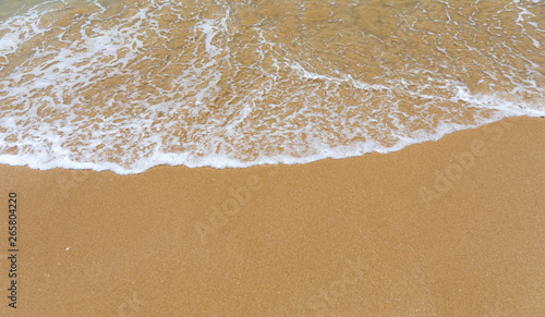 Blue ocean wave on sandy beach. Soft wave of blue ocean on sandy beach. Background. Top view of Beautiful beach with tranquil wave, sea and ocean background, summer vacation concept.